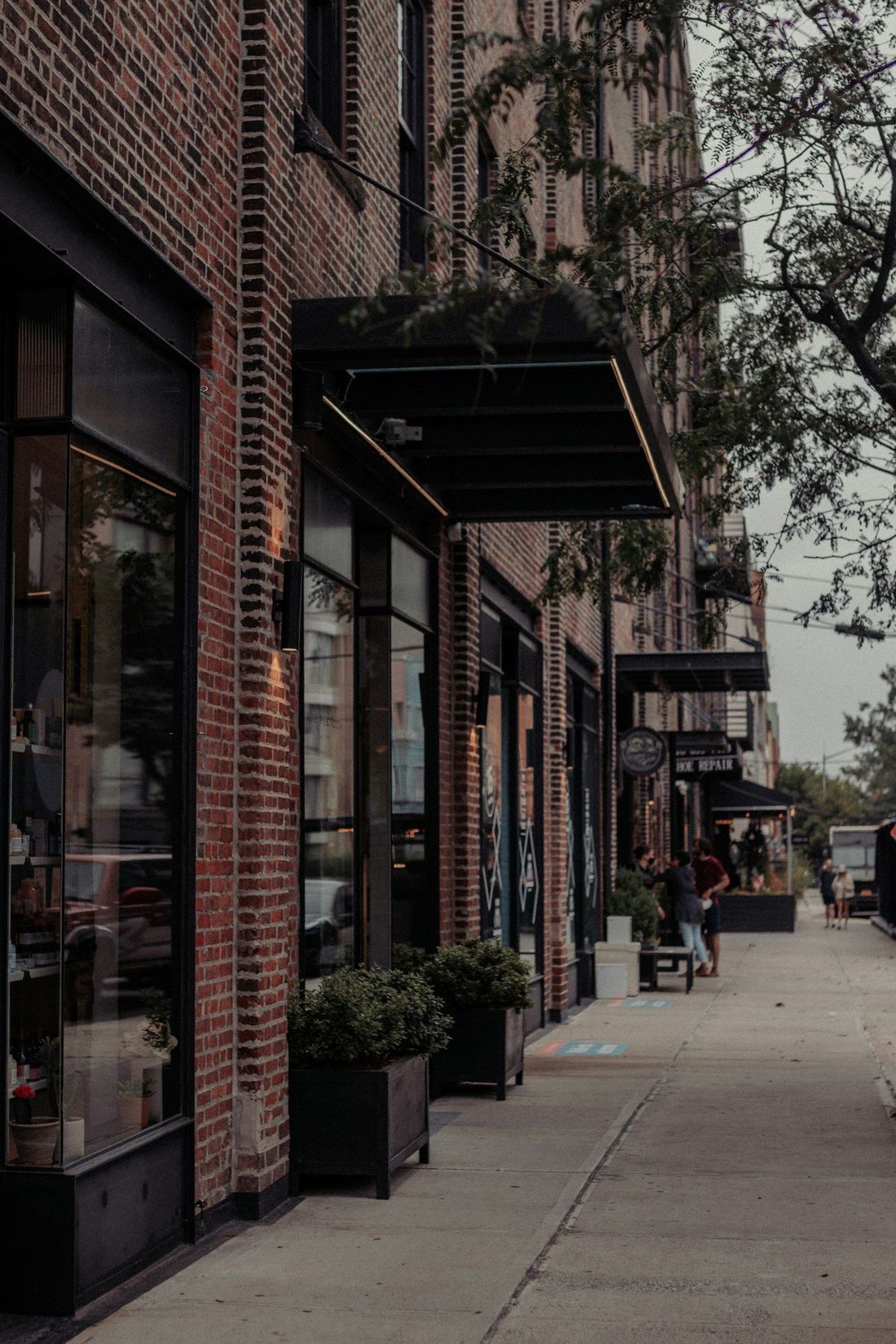 Storefronts along a brick building on a New York sidewalk